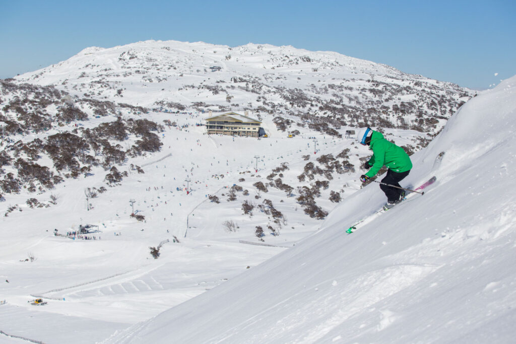 Image of skier in Green jacket going down a run in Perisher on a sunny day