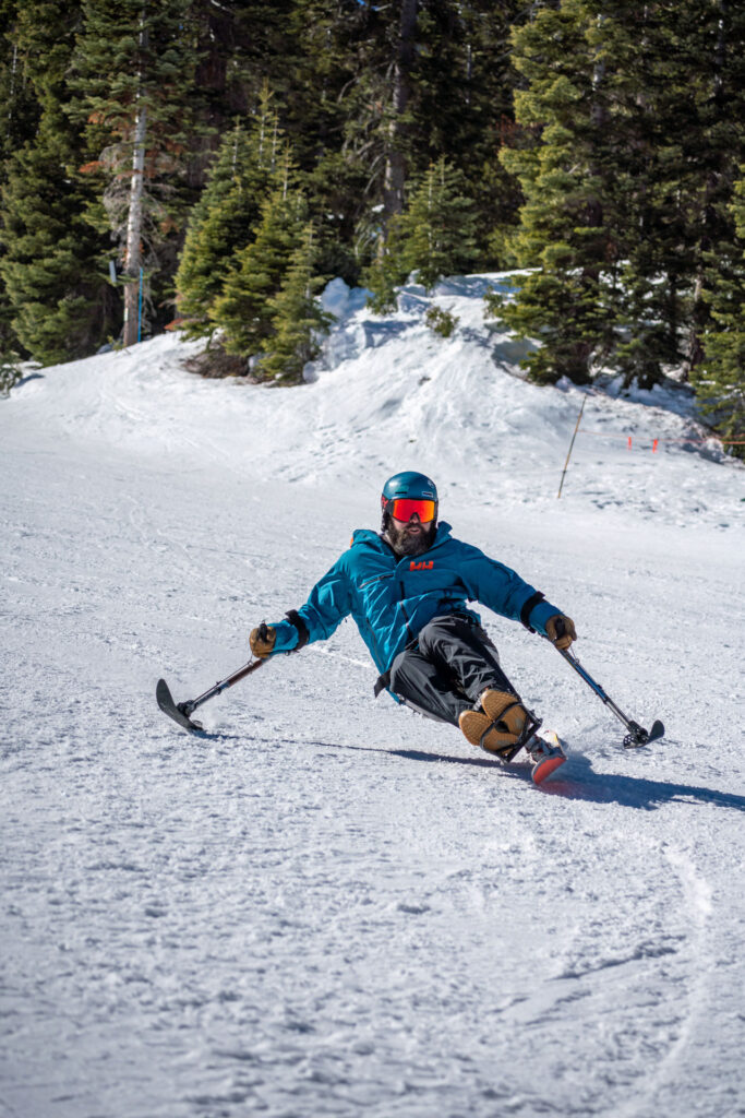 Sit skier in a blue jacket skiing down a run