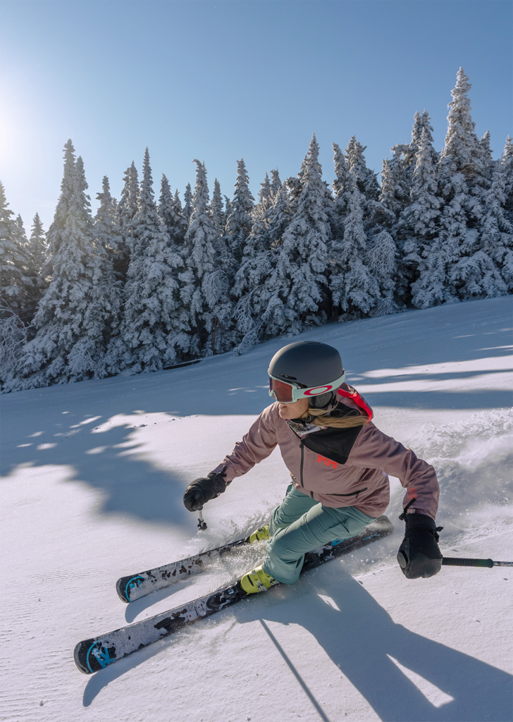 Skier in pink jacked carving a turn on a groomed run