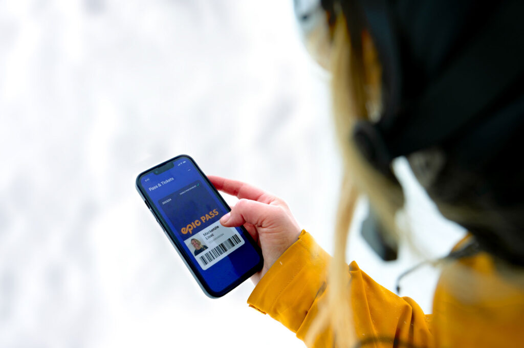 Image of skier holding phone while looking at my epic app and loading their mobile pass
