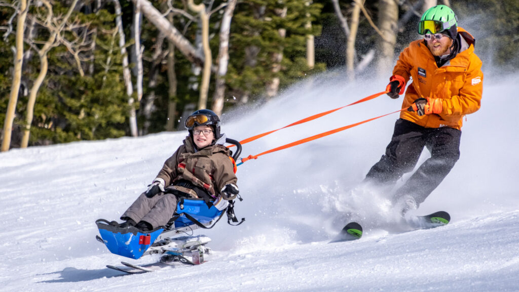 Sit skier with tether partner skiing behind