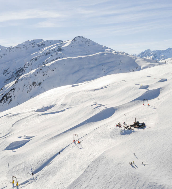 Aerial view of the terrain at Andermatt in Switzerland with a lodge and a group of skiers in view