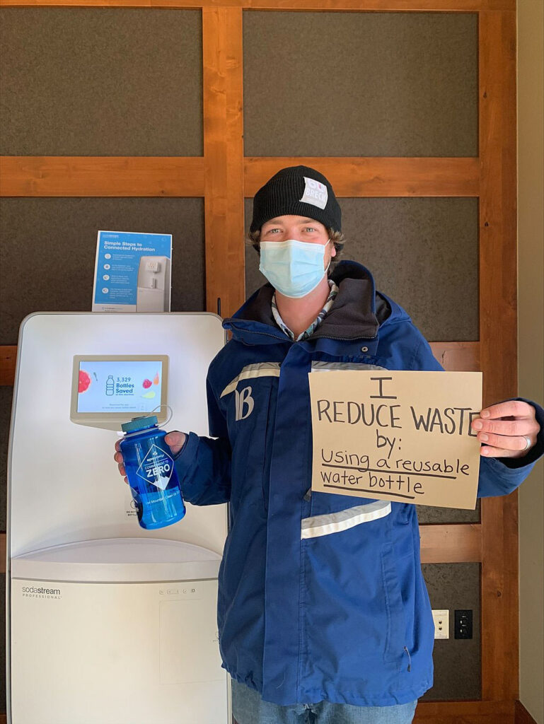 Breckenridge employee holding sign that says "I reduce waste by: using a reusable water bottle"