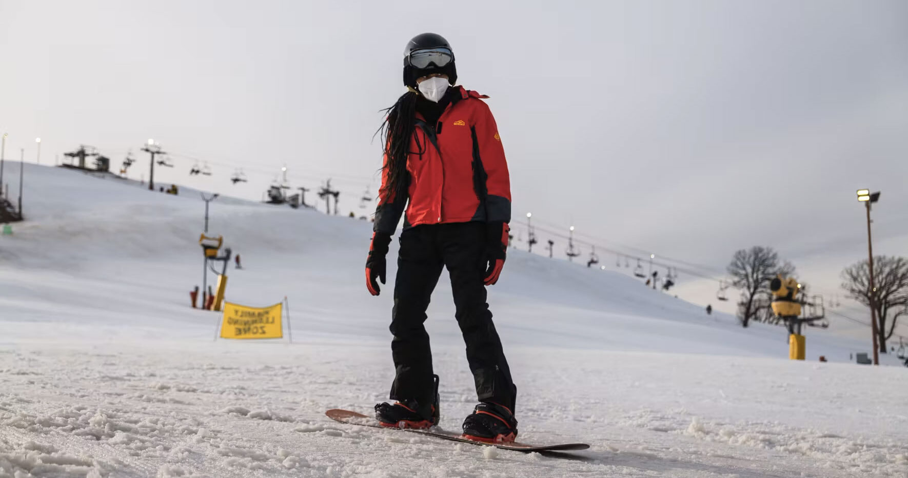 Girl snowboarding wearing red jacket and black pants