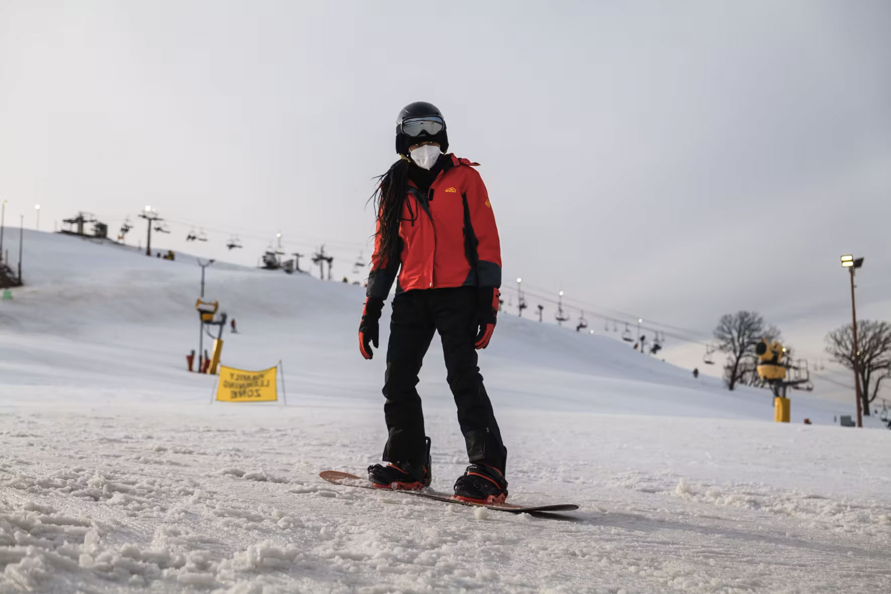 Girl snowboarding wearing red jacket and black pants