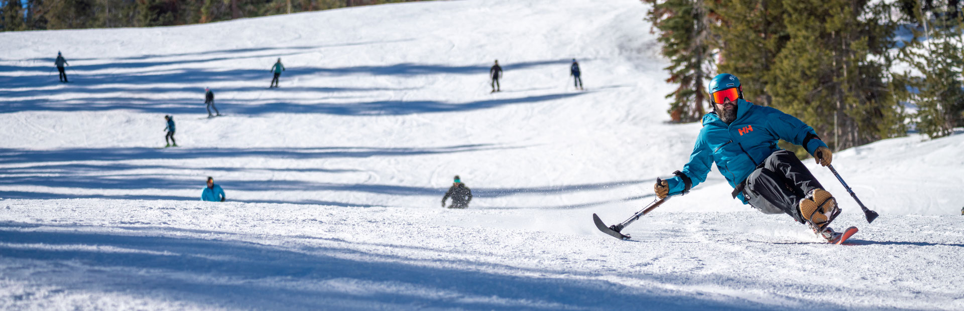 Skier skiing downhill in adaptive chair in blue jacket