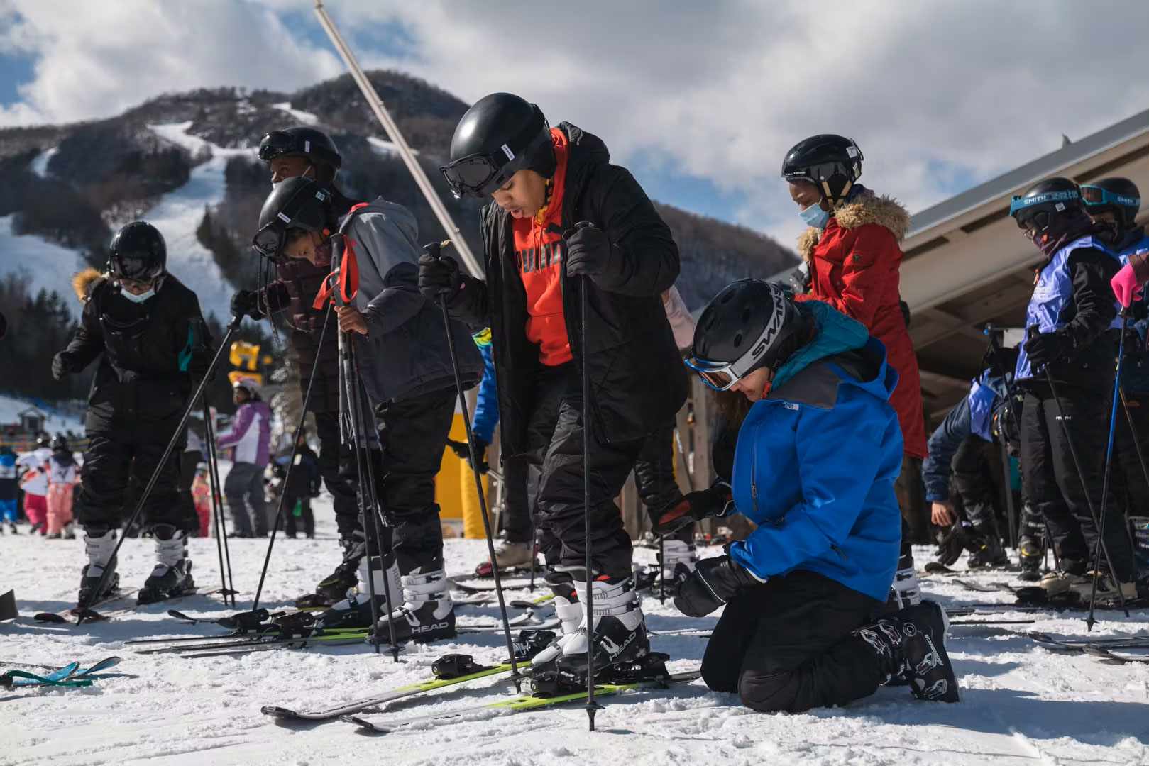 Ski instructor helping young skier with his equipment at ski resort