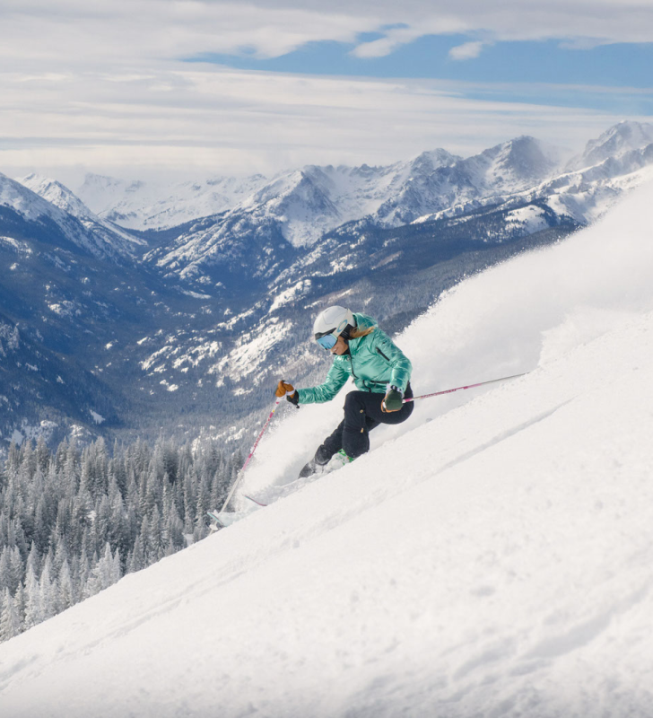 Image of skier in green coat skiing at vail on sunny day