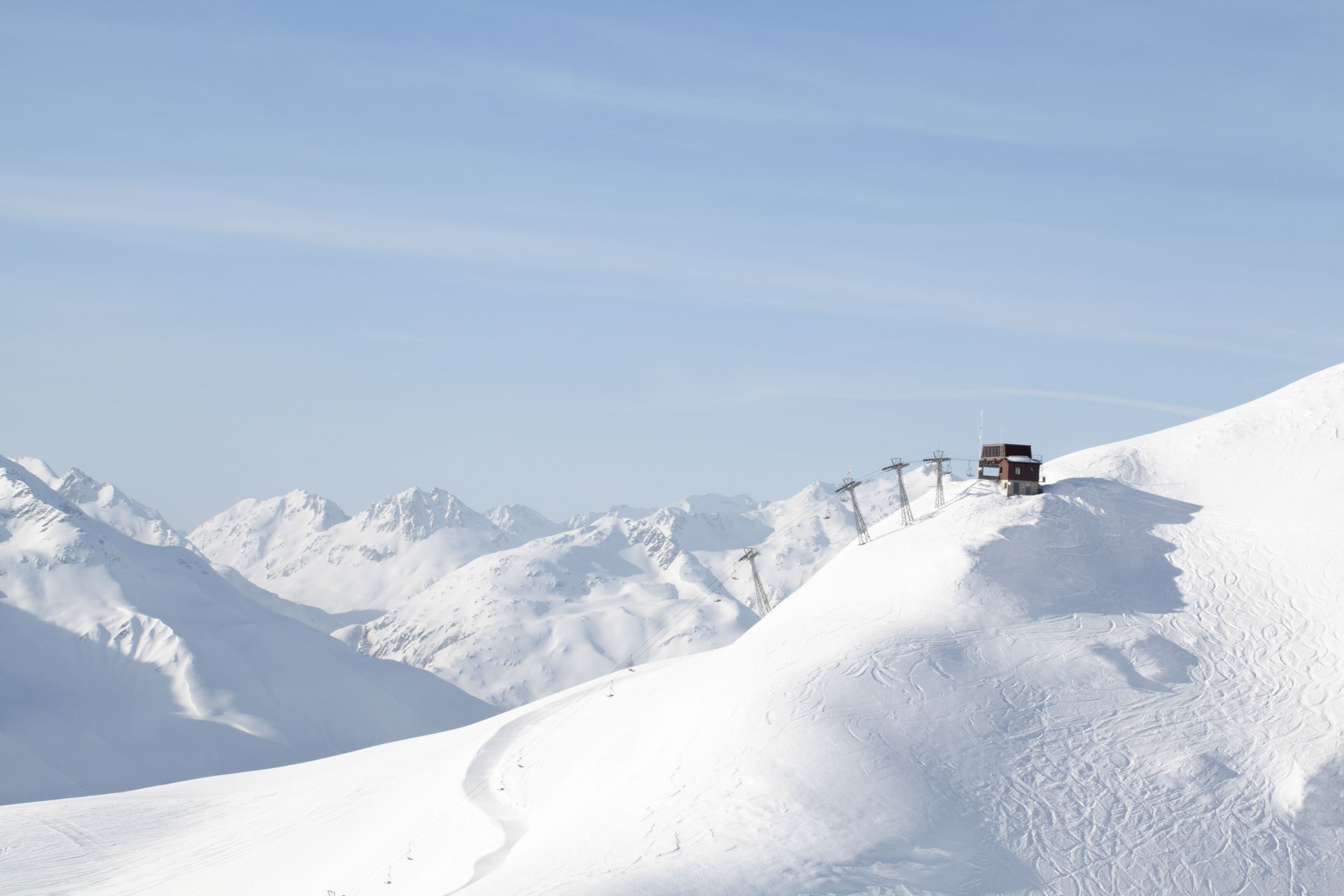 Scenic wither image of ski lift in Switzerland with big peaks and blue skies