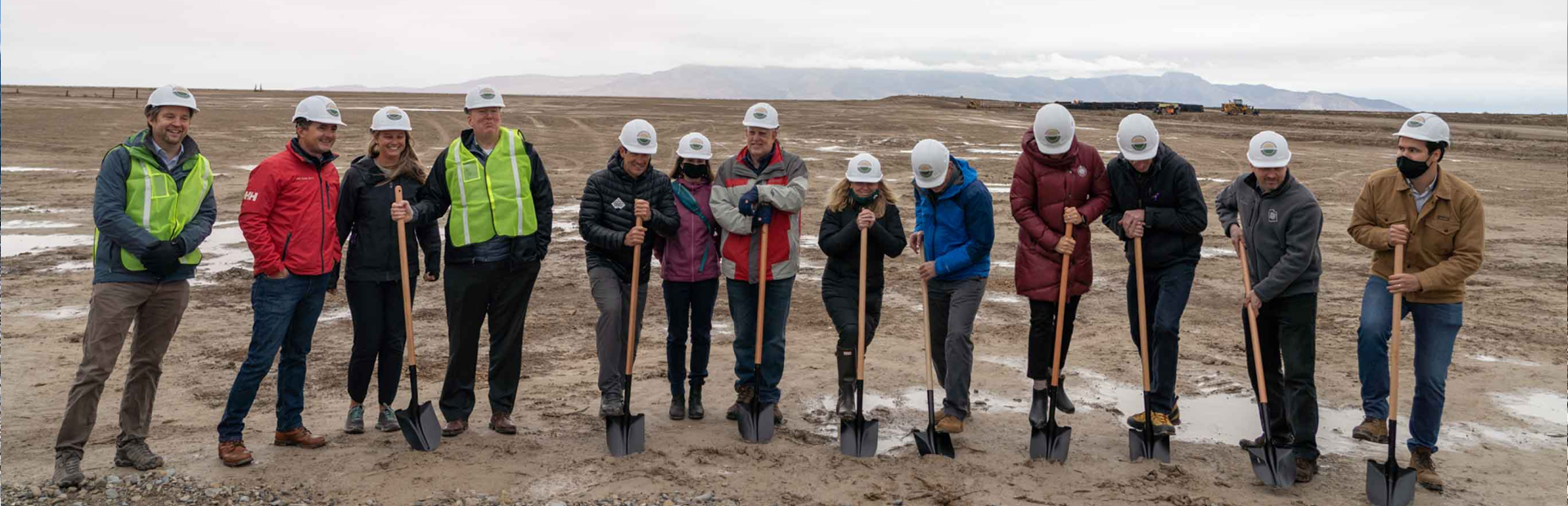 Group of 13 people putting shovels into the ground to symbolize the groundbreaking of the solar farm