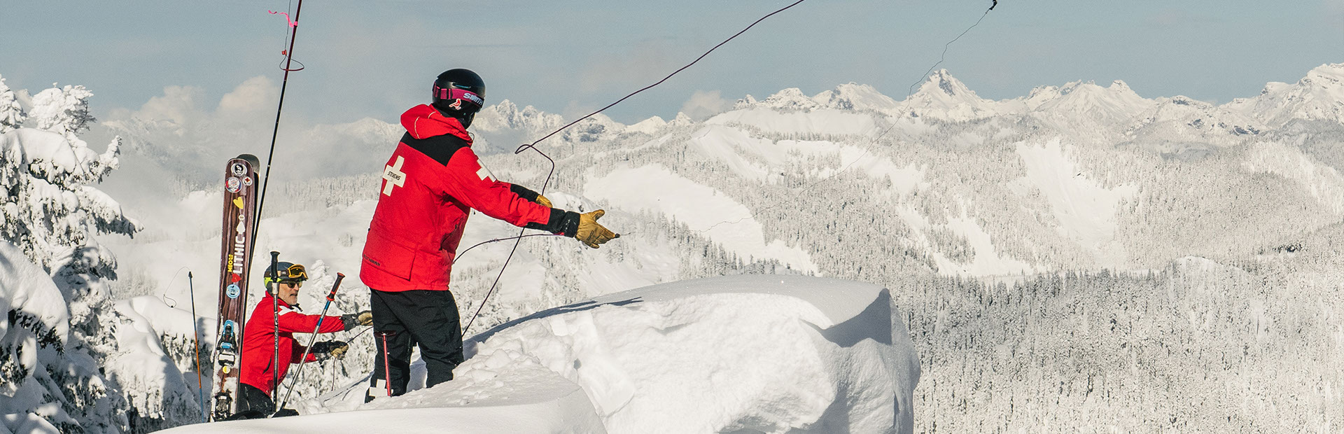 2 ski patrollers throwing a cable over a corneous 