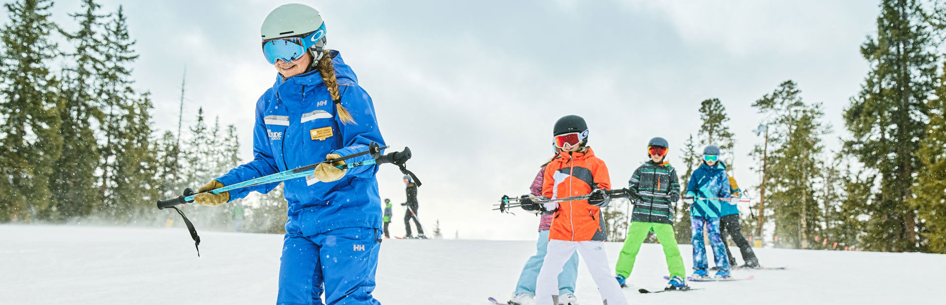 Ski instructor skiing downhill with students skiing behind her