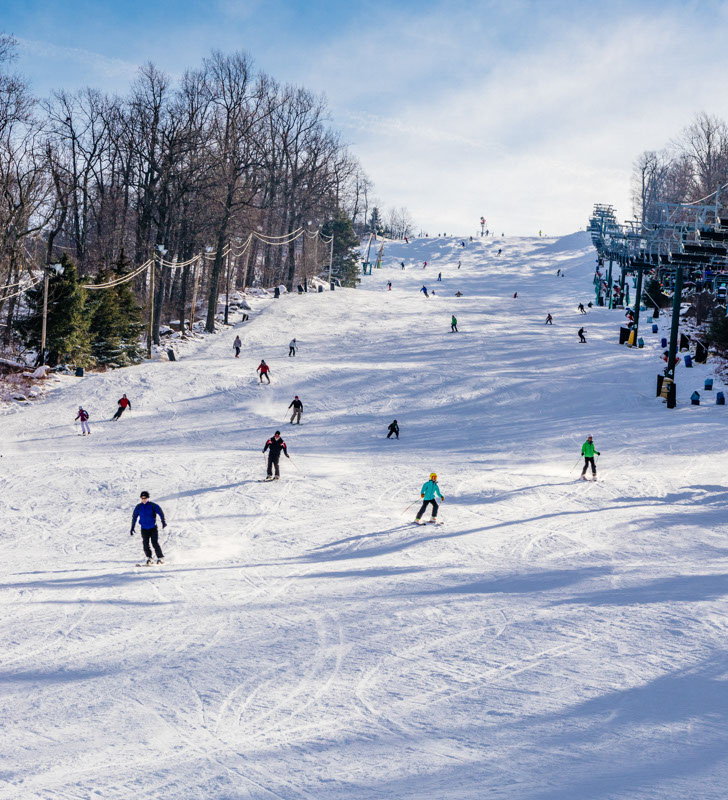 Skiers and Riders Make Turns Downhill at Roundtop