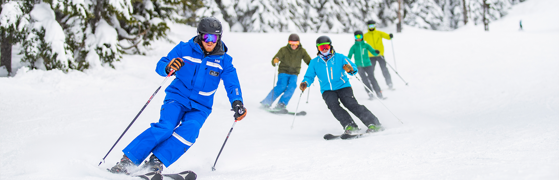 Ski instructor leading adults down groomed trail