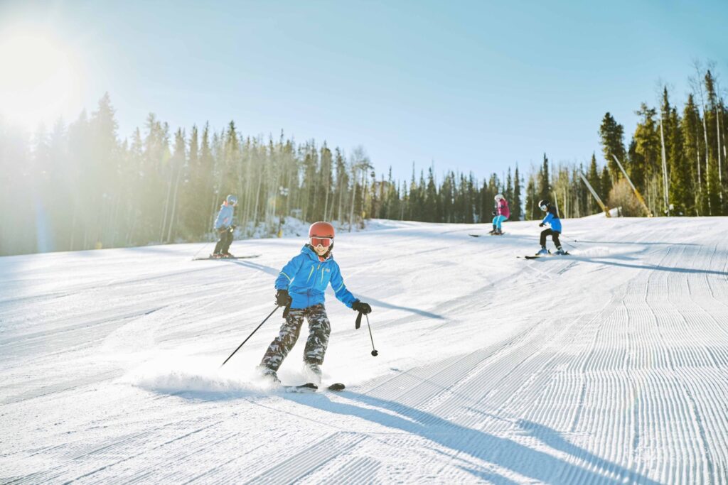 Family skiing a freshly groomed ski slope on a sunny day