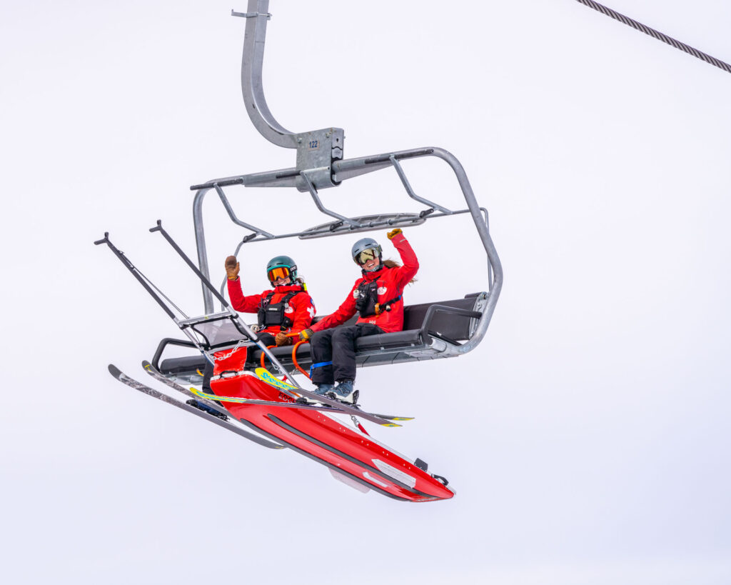Two female ski patrollers on a chairlift