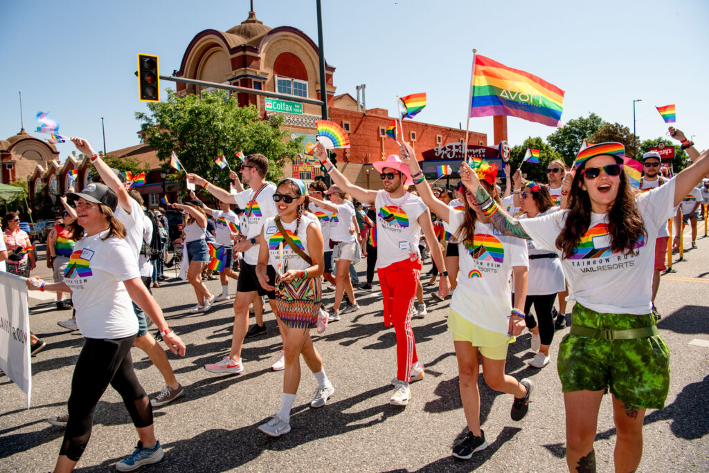Group of Vail employees wearing Rainbow Room Vail Resorts logo shirts participating in a pride parade