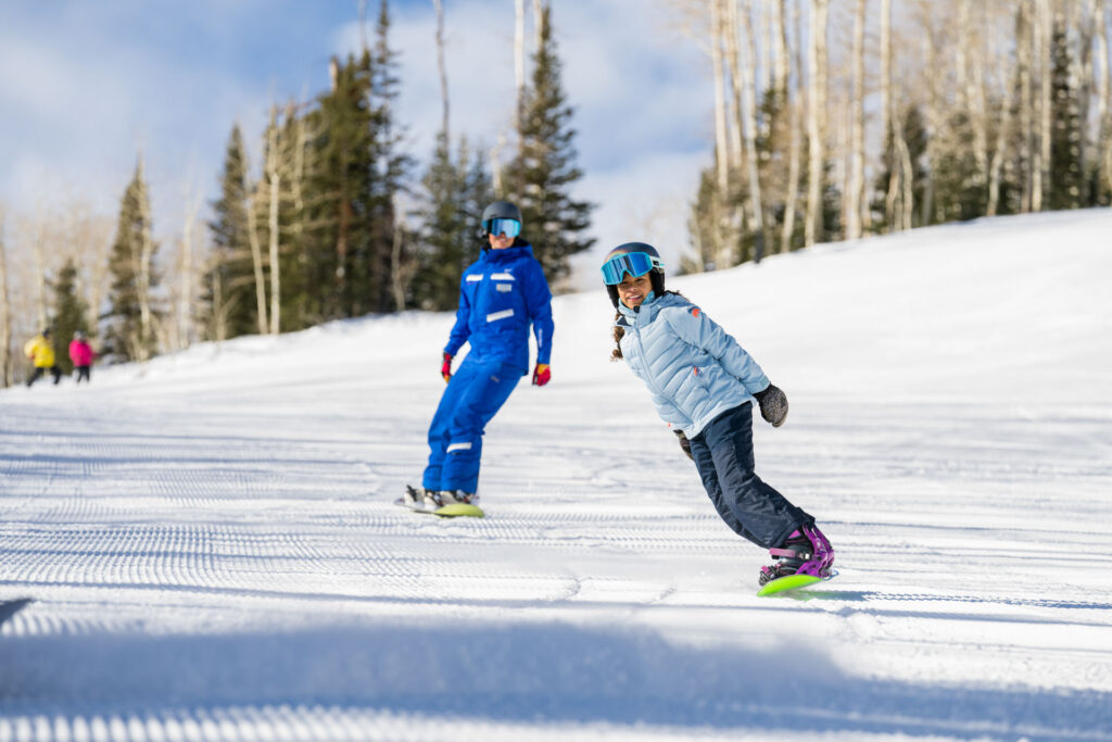 Young girl snowboarding in front on instructor