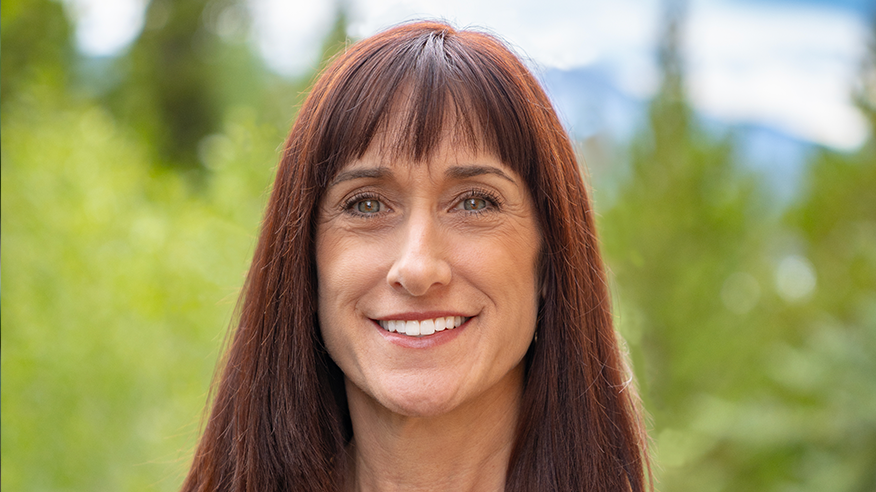Woman with red-ish brown hair and bangs smiling